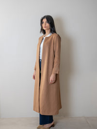 Femme portant un manteau élégant camel femme, look chic et moderne, style automne/hiver, collection Ambjaya.