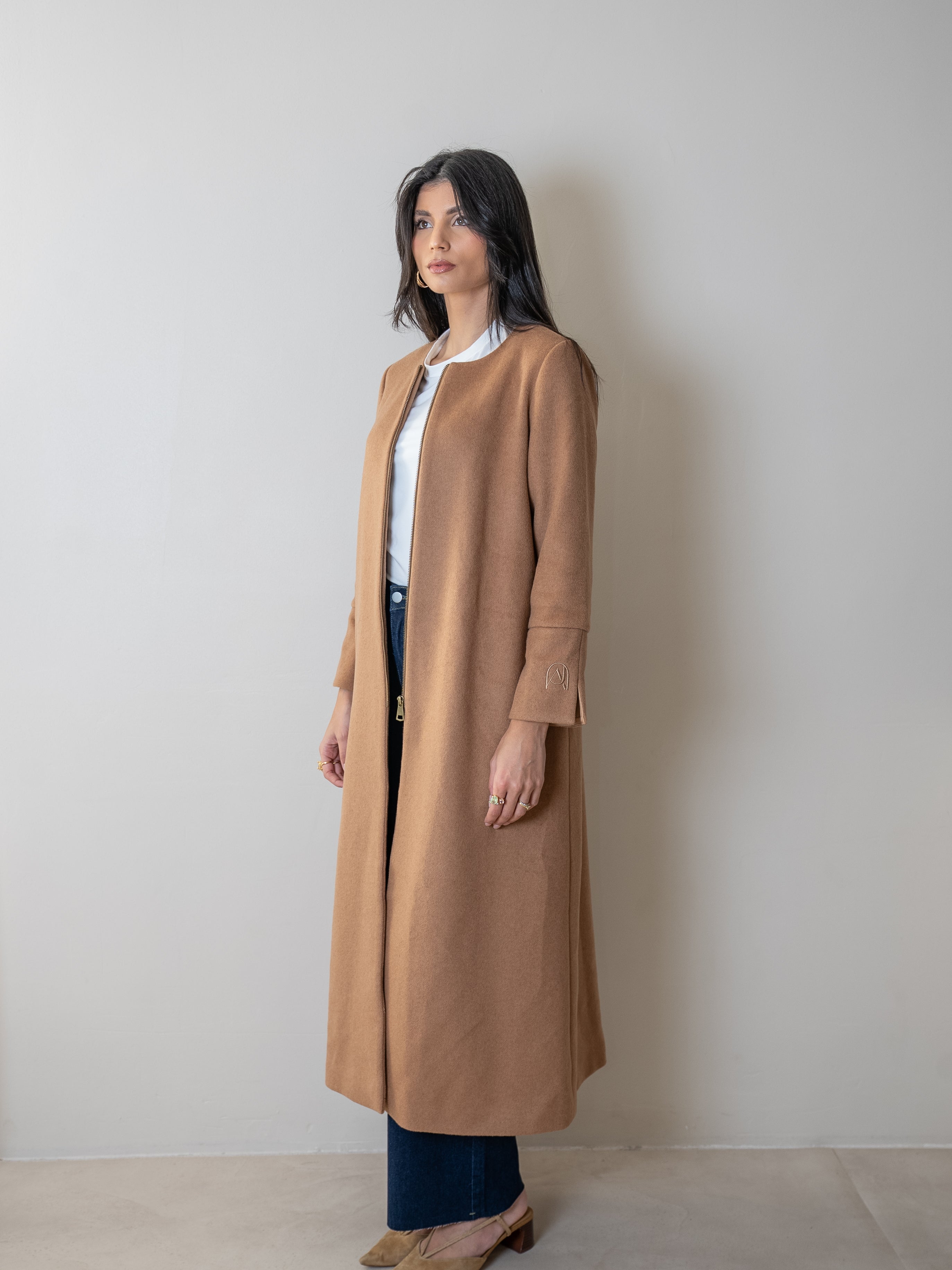 Femme portant un manteau élégant camel femme, look chic et moderne, style automne/hiver, collection Ambjaya.